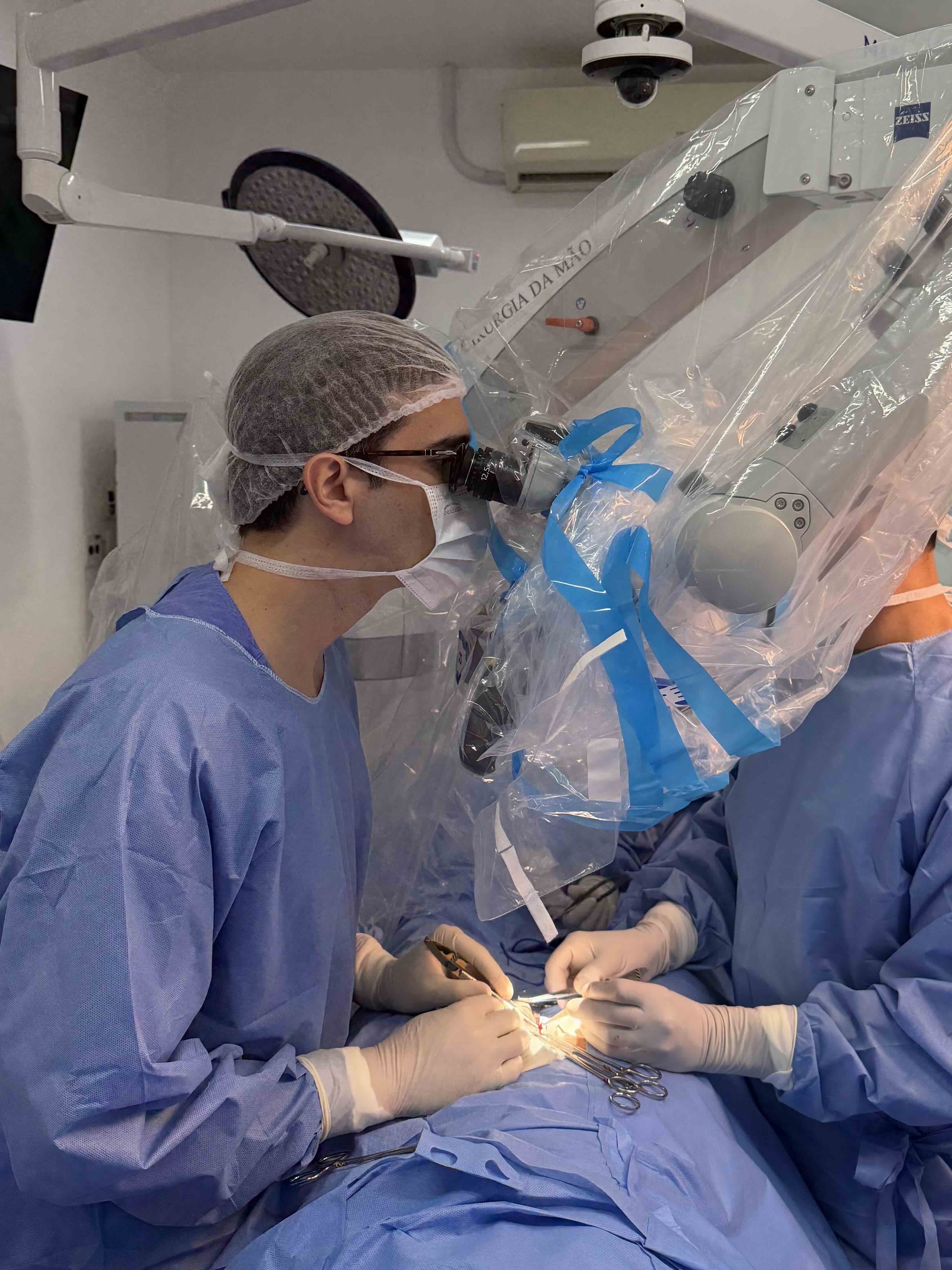 Dr. Henrique Cury Fernandes realizando reversão de vasectomia em centro cirúrgico com microscópio